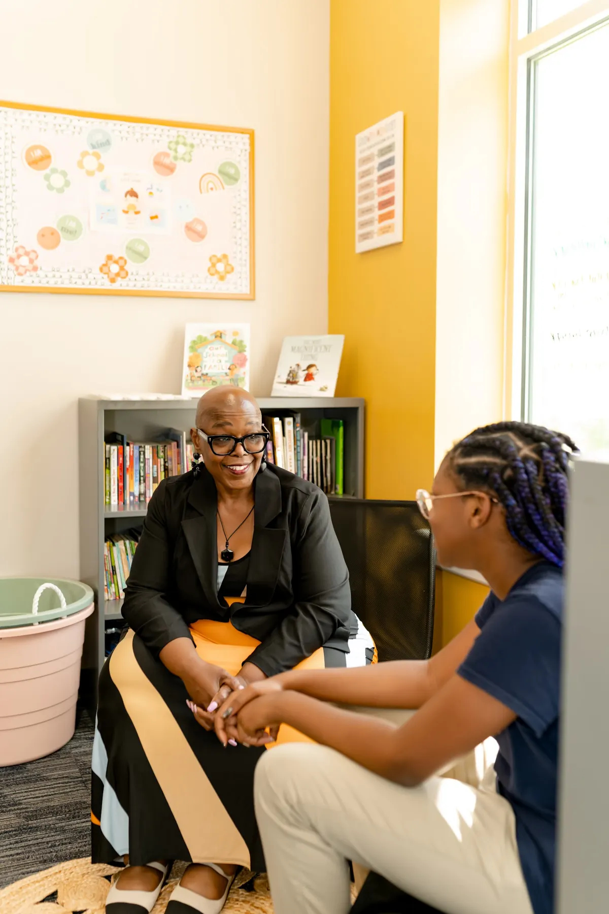 Angelia Moore sitting with a student in a classroom reading corner